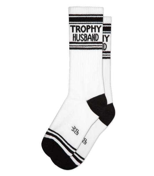 White athletic crew socks with black stripes and trophy husband text on cuff featuring small toe logo