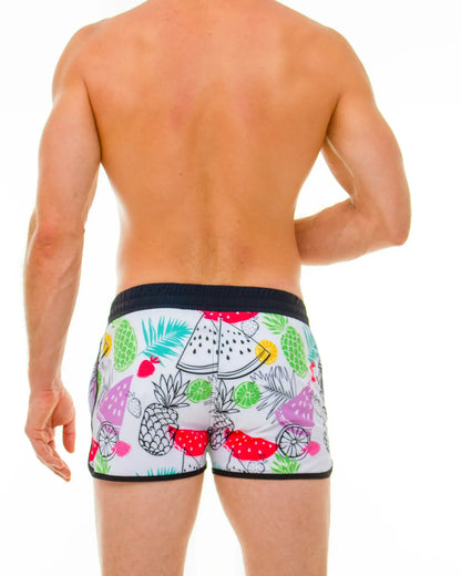 White swim trunks with a vibrant tropical fruit pattern of pineapples watermelon and limes in bright colors