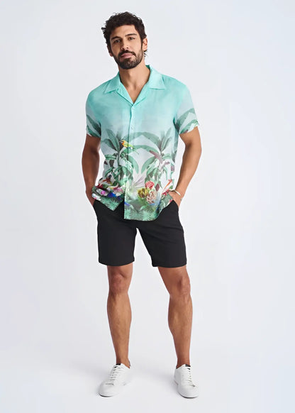 A men’s short-sleeved turquoise modal shirt with a detailed tropical print featuring foliage and colorful birds