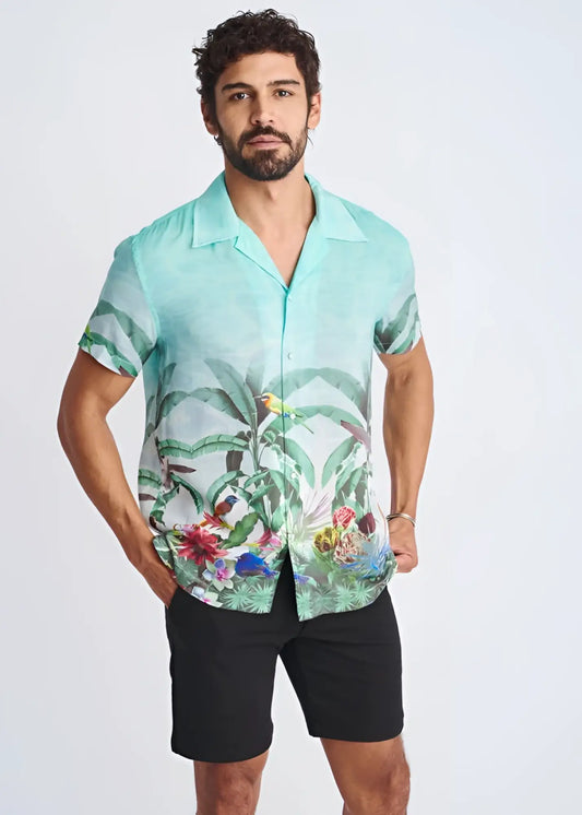 A men’s short-sleeved button-up modal shirt in vibrant turquoise with tropical green leaves and colorful birds print