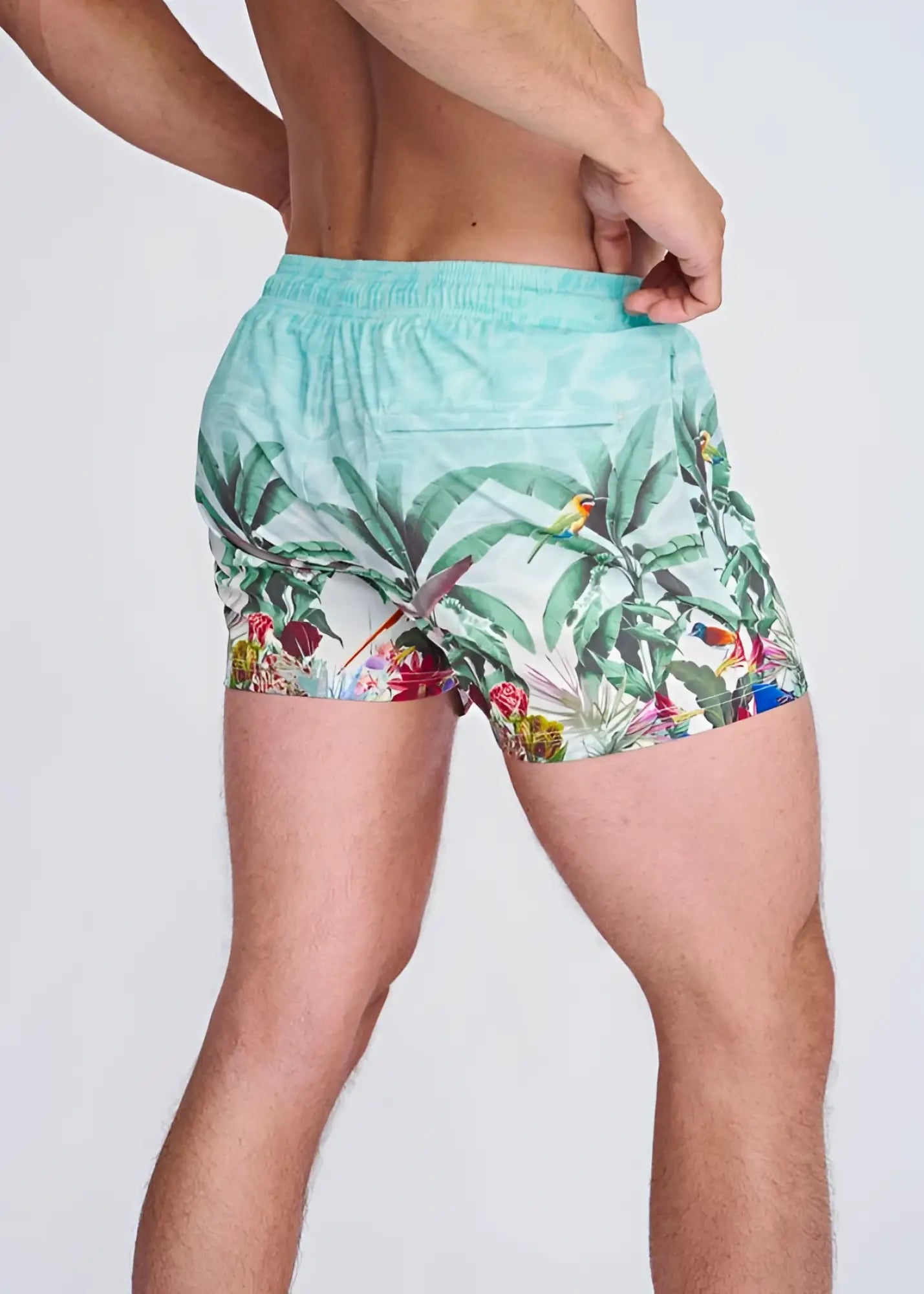 Light blue tropics print swim shorts with mesh lining featuring vibrant green leaves colorful birds and red flowers