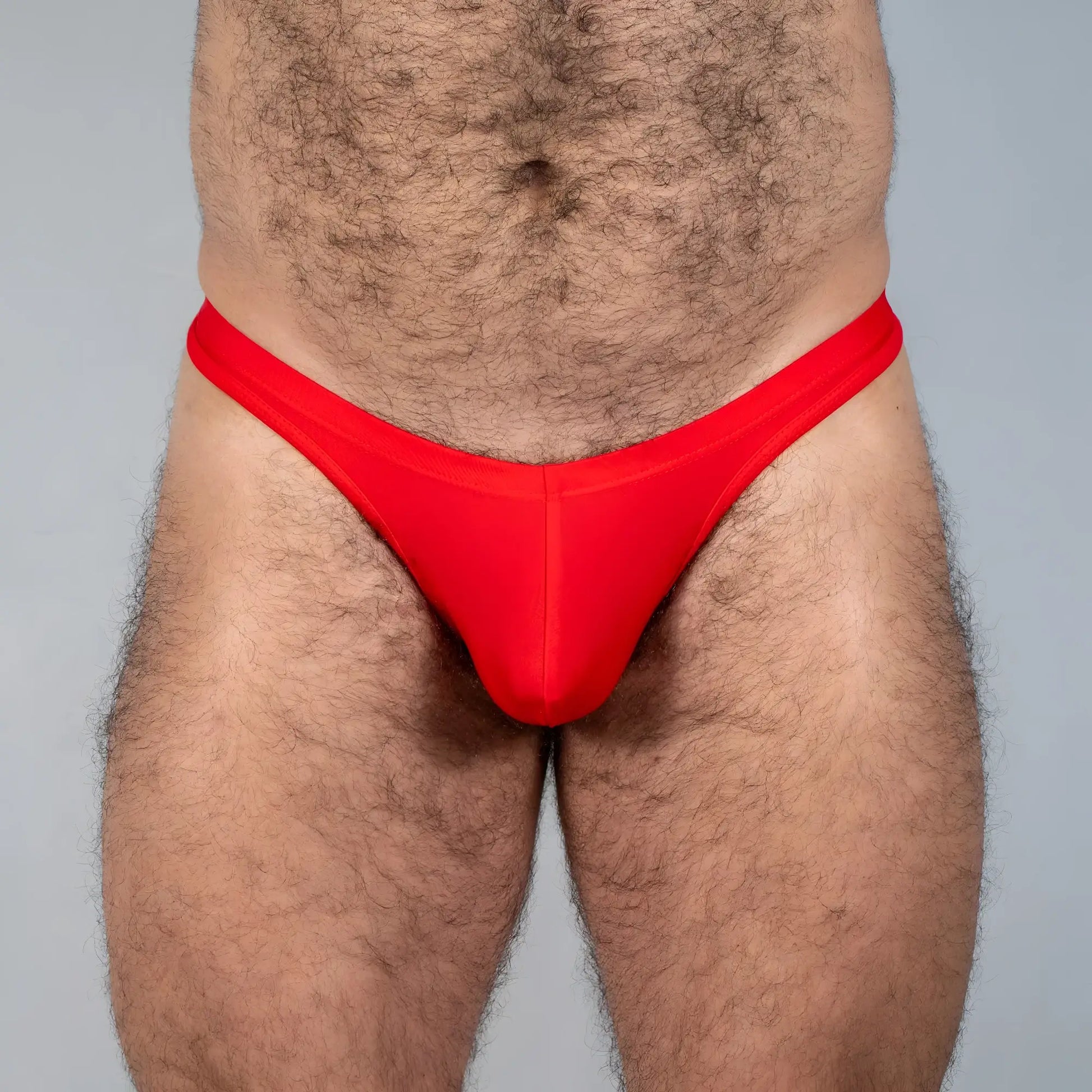Bright red Tulio swim thong made of smooth stretchy fabric with a form-fitting design shown from the back side