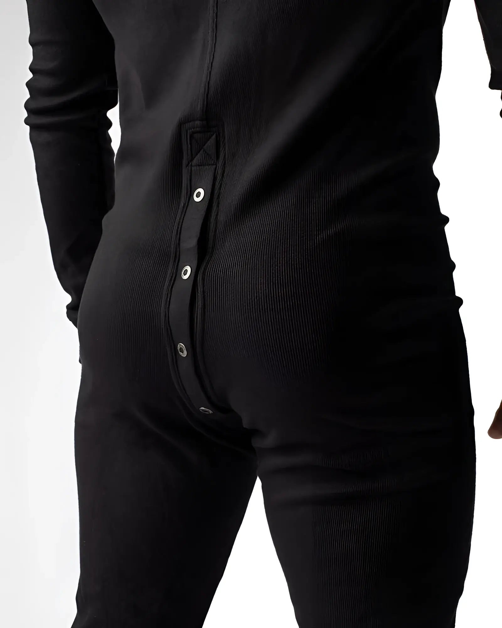 Black ribbed knit union suit pajama shown from the back with a vertical row of silver snap buttons down the spine