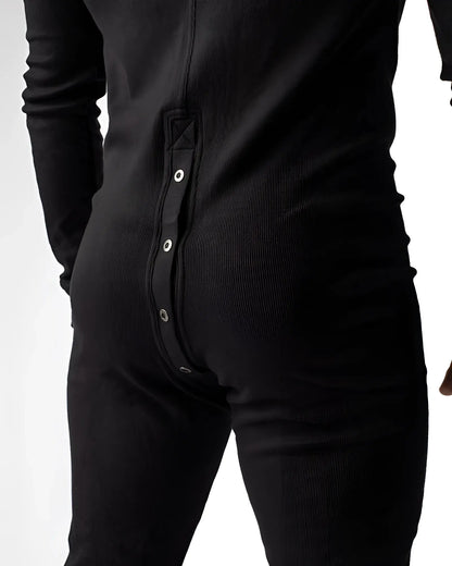 Black ribbed knit union suit pajama shown from the back with a vertical row of silver snap buttons down the spine