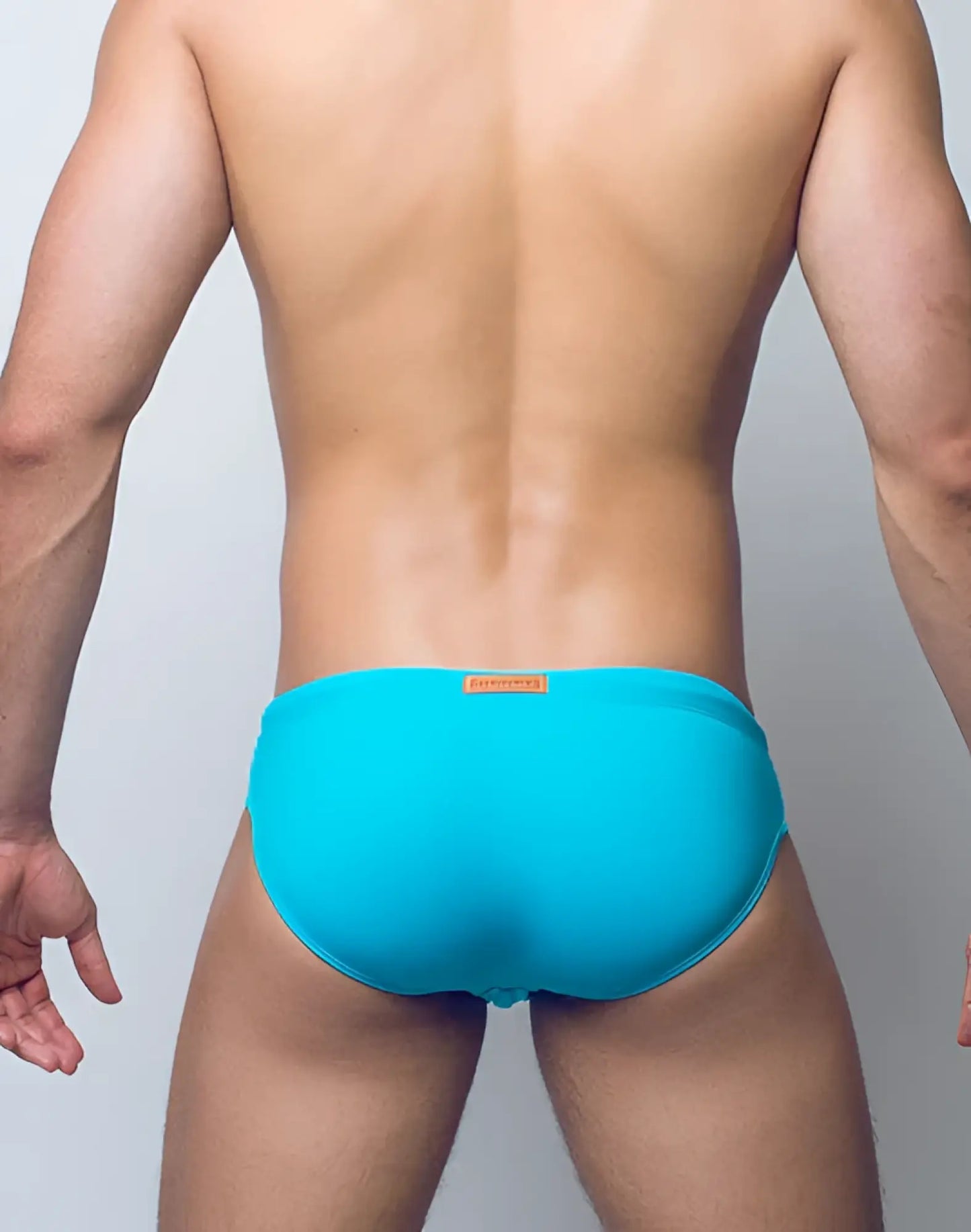 Bright turquoise v10 core bikini swim trunks with a small orange brand tag at the waistband for swimming use
