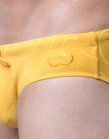 Bright yellow V10 ripple textured swim brief with subtle pattern and embroidered infinity symbol on the front