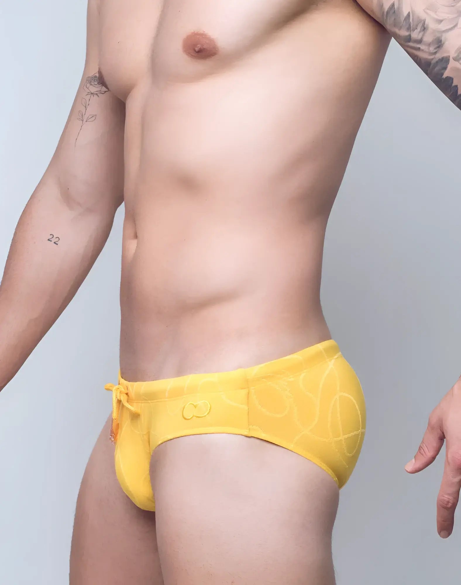 Bright yellow v10 ripple textured swim brief with subtle abstract pattern and orange drawstring for swimming