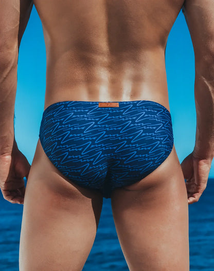 Blue swim trunks v20 signature print swim brief with light blue abstract line pattern and orange brand tag at waistband