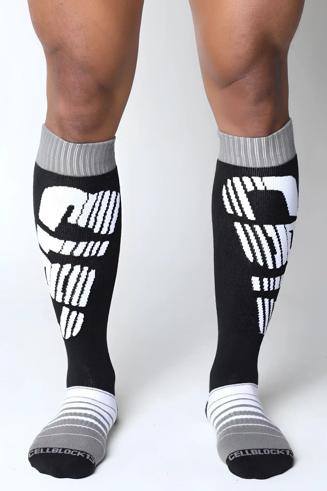 Black and white velocity 2.0 knee high compression socks with bold skull design on calf in back view
