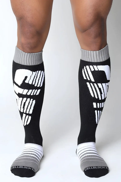 Black and white velocity 2.0 knee high compression socks with bold skull design on calf in back view