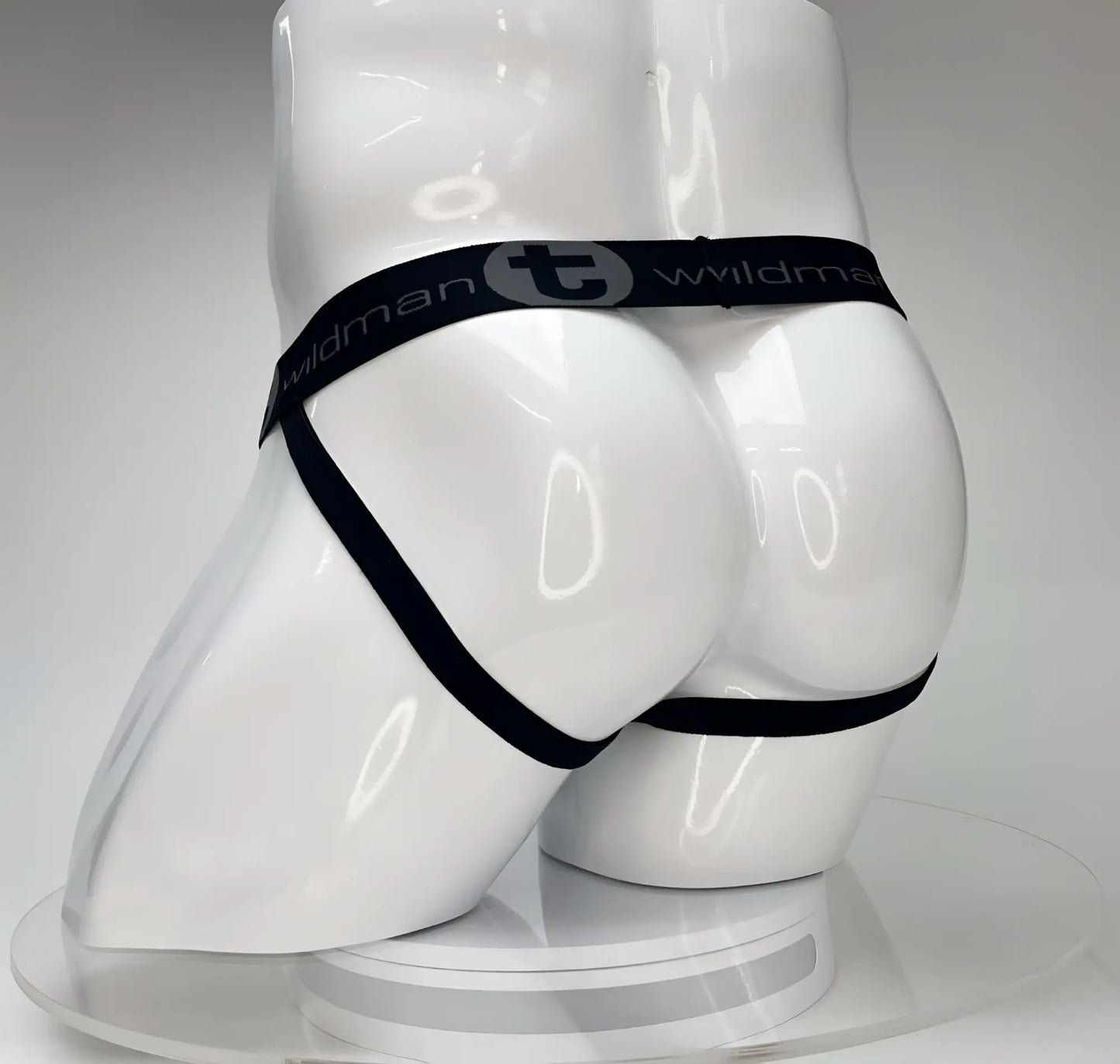 Black elastic waistband with wildman branding on white glossy mannequin featuring wildmant big boy pouch jockstrap white