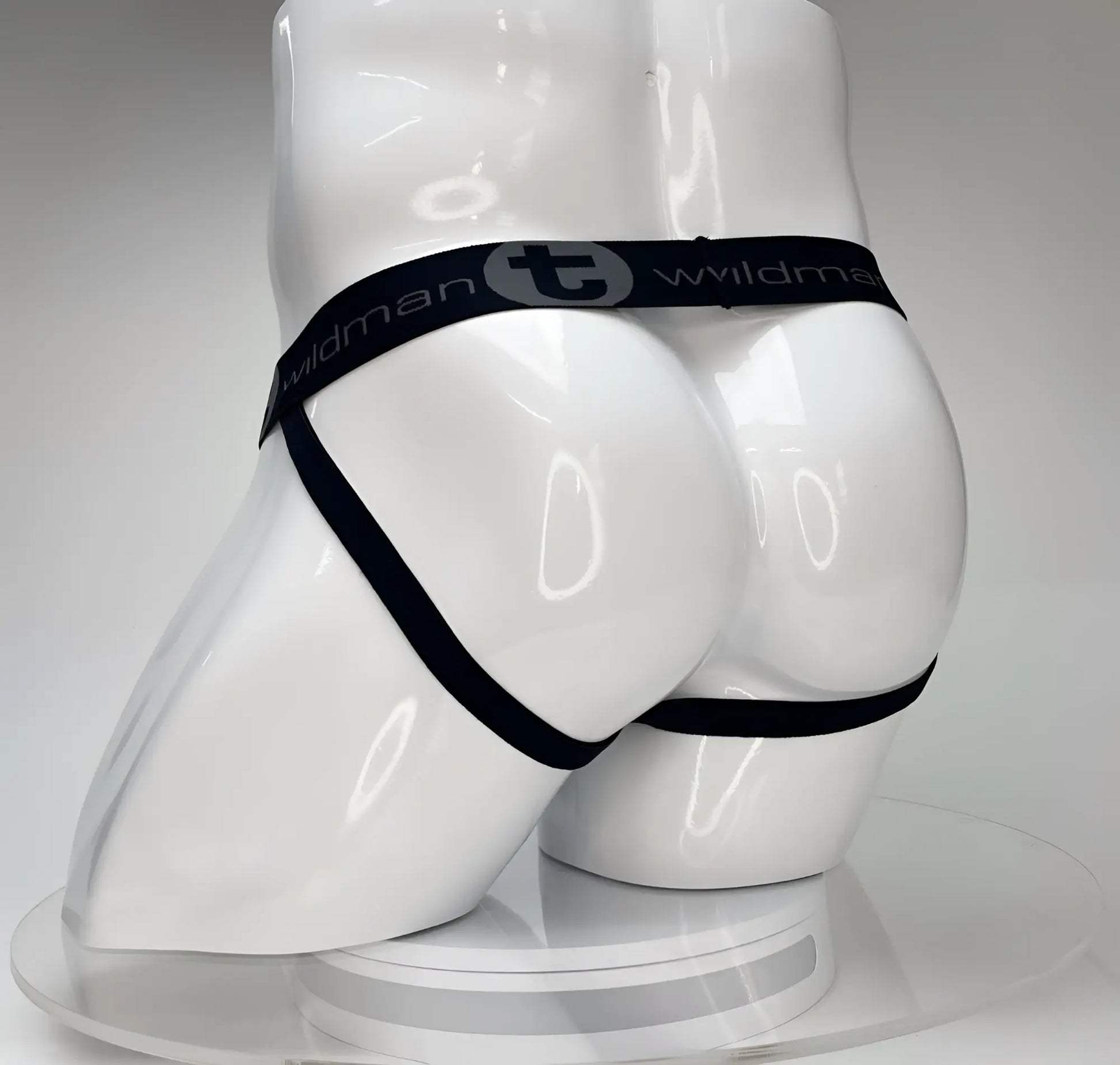 Black elastic waistband with wildman branding on white glossy mannequin featuring wildmant big boy pouch jockstrap white