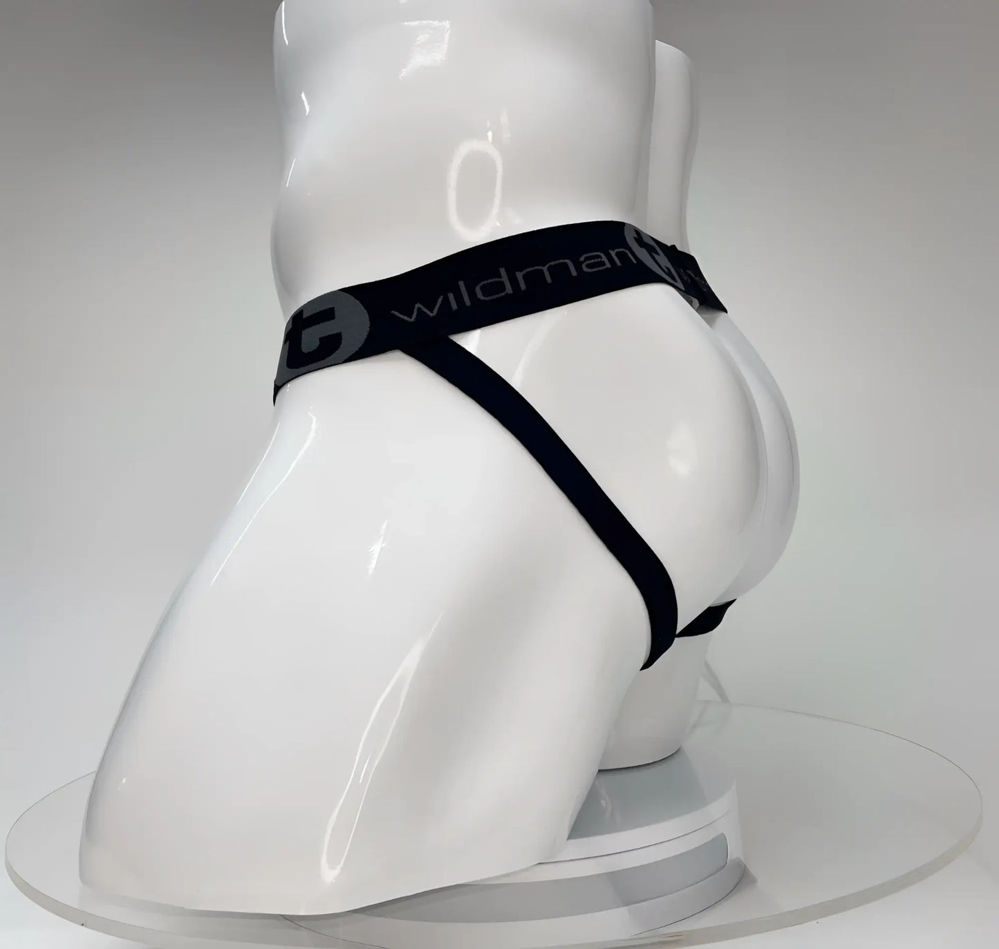 WildmanT Big Boy white jockstrap on a white mannequin featuring a black elastic waistband with brand logo branding.