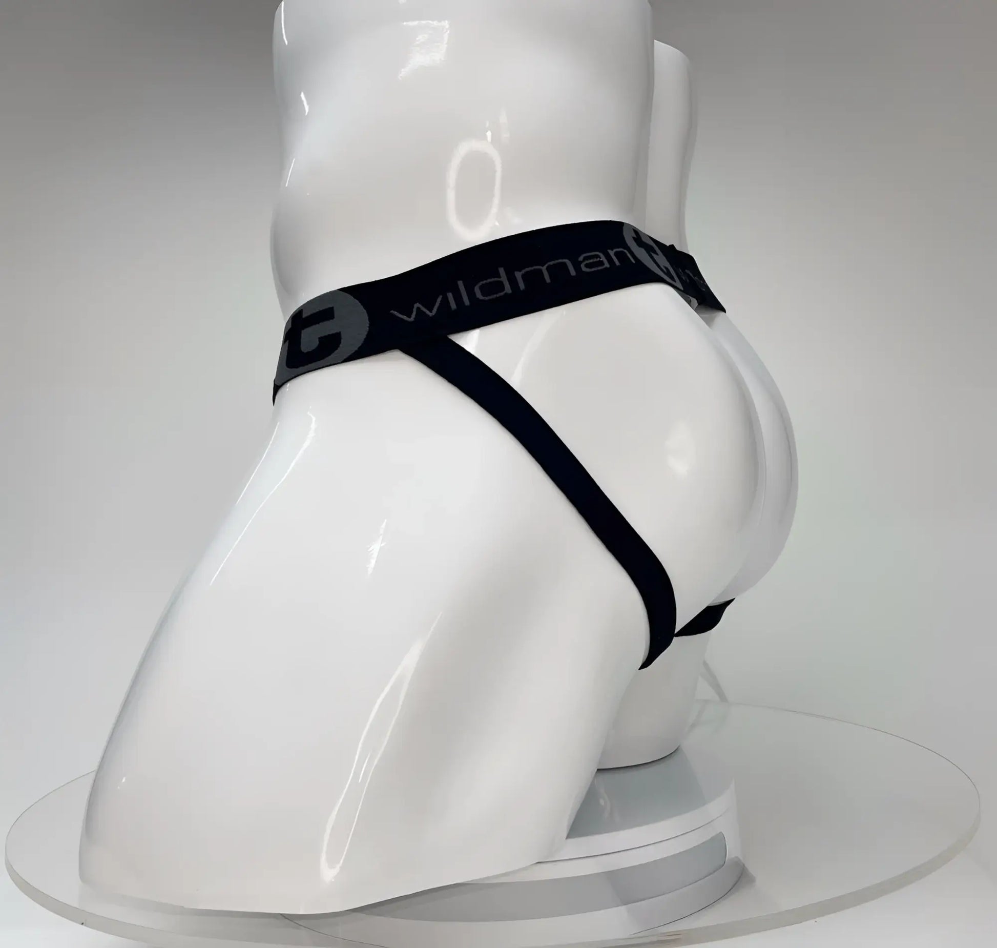WildmanT Big Boy white jockstrap on a white mannequin featuring a black elastic waistband with brand logo branding.