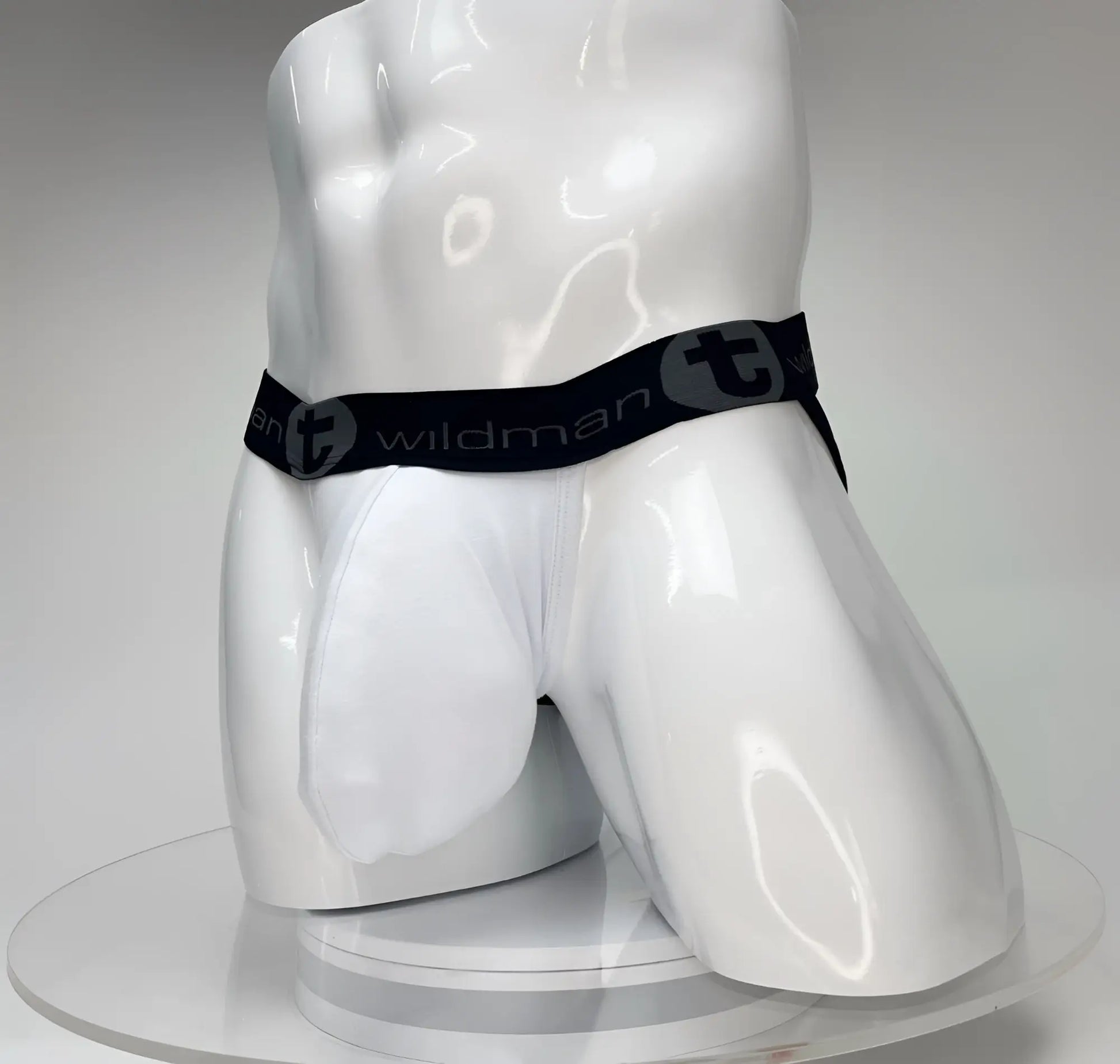 White WildmanT Big Boy pouch jockstrap on a glossy white mannequin, featuring a black branded waistband.