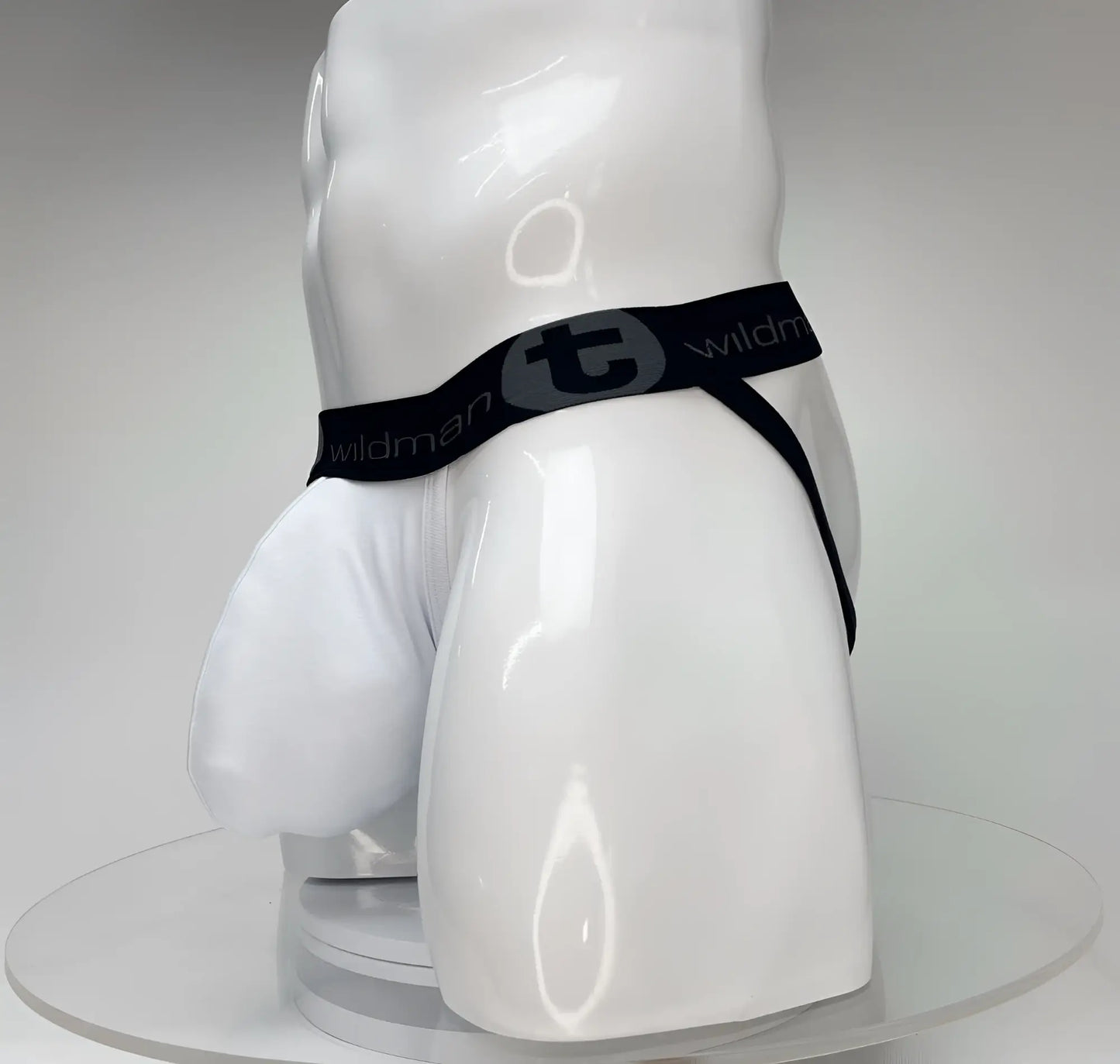 White jockstrap with a large pouch on a white mannequin, featuring a black branded waistband with a WildmanT logo.