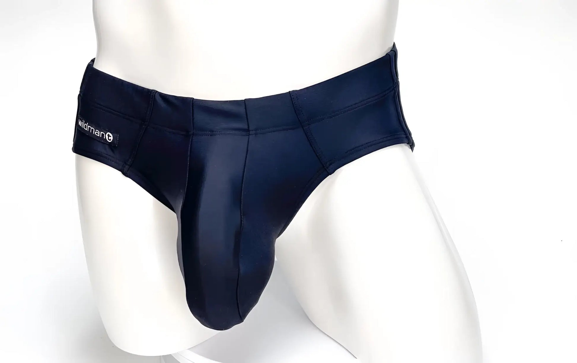 Black WildmanT swim brief with a large contour pouch, worn on a white mannequin with brand logo tag on the side.