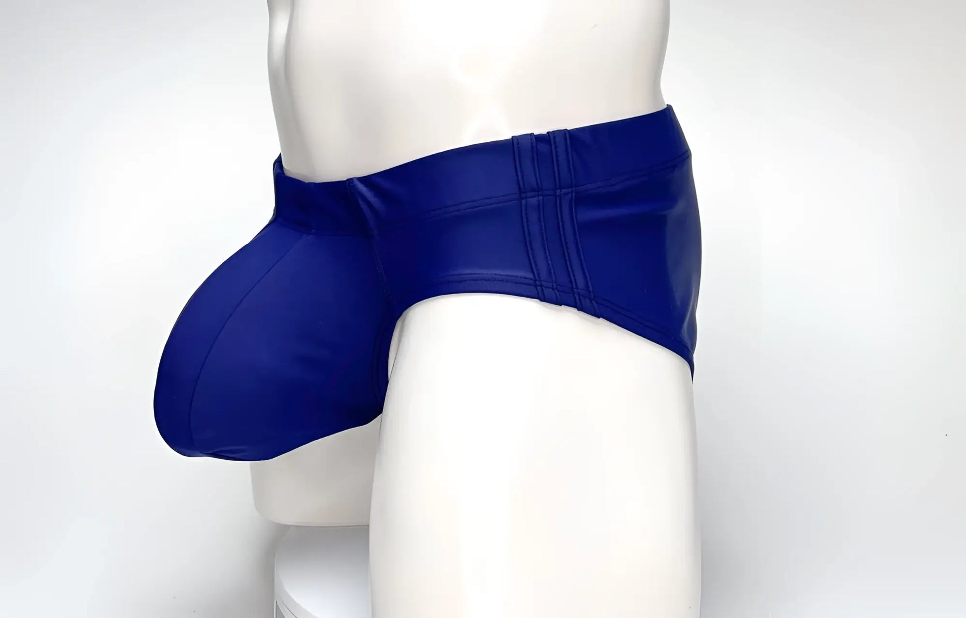 WildmanT navy blue swim brief featuring a prominent, rounded front pouch and contoured side panels on a mannequin.
