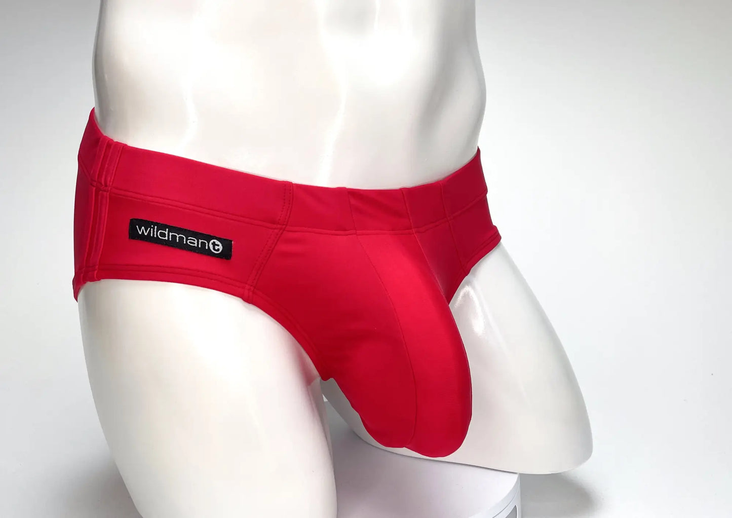 Bright red form-fitting swim brief with black wildman brand label on waistband designed for big boy pouch support