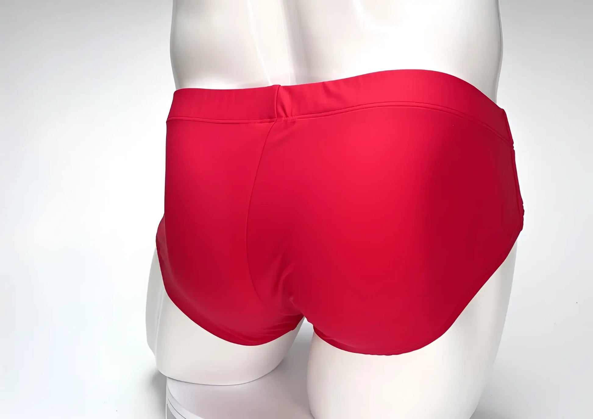Back view of a solid red WildmanT Big Boy pouch swim brief on a white mannequin torso.