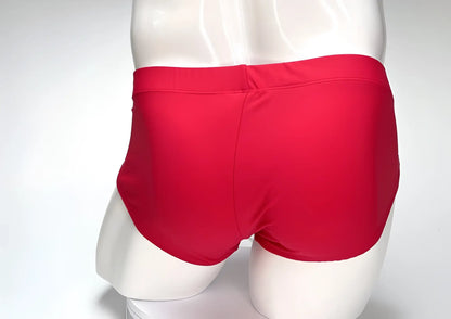 Back view of a WildmanT red swim brief on a white mannequin, featuring a smooth, form-fitting fabric design.