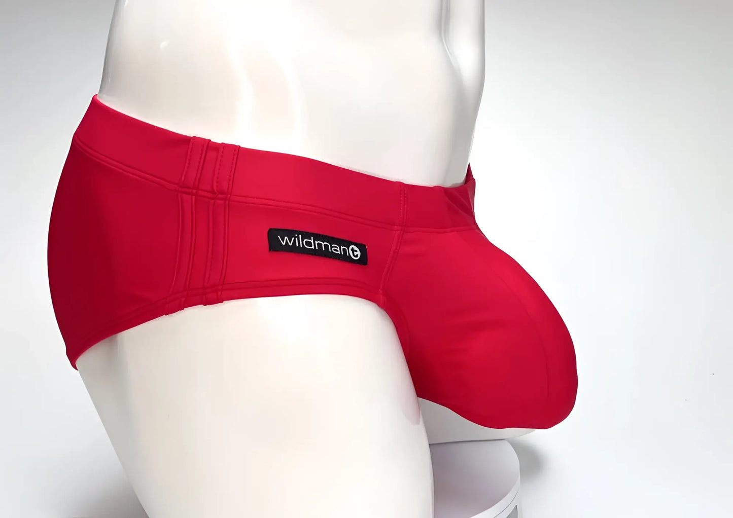 WildmanT red swim brief on a mannequin, featuring a prominent, rounded front pouch and a side-mounted brand tag.