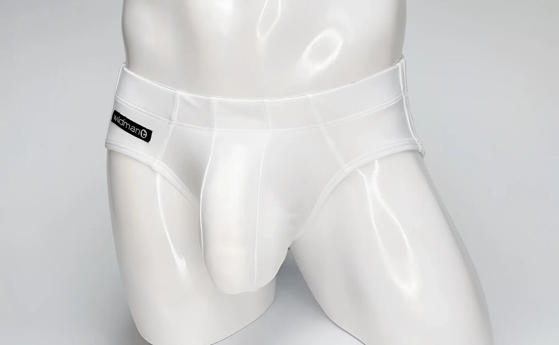 White WildmanT Big Boy pouch swim brief on a white mannequin with a branded black logo patch on the side.