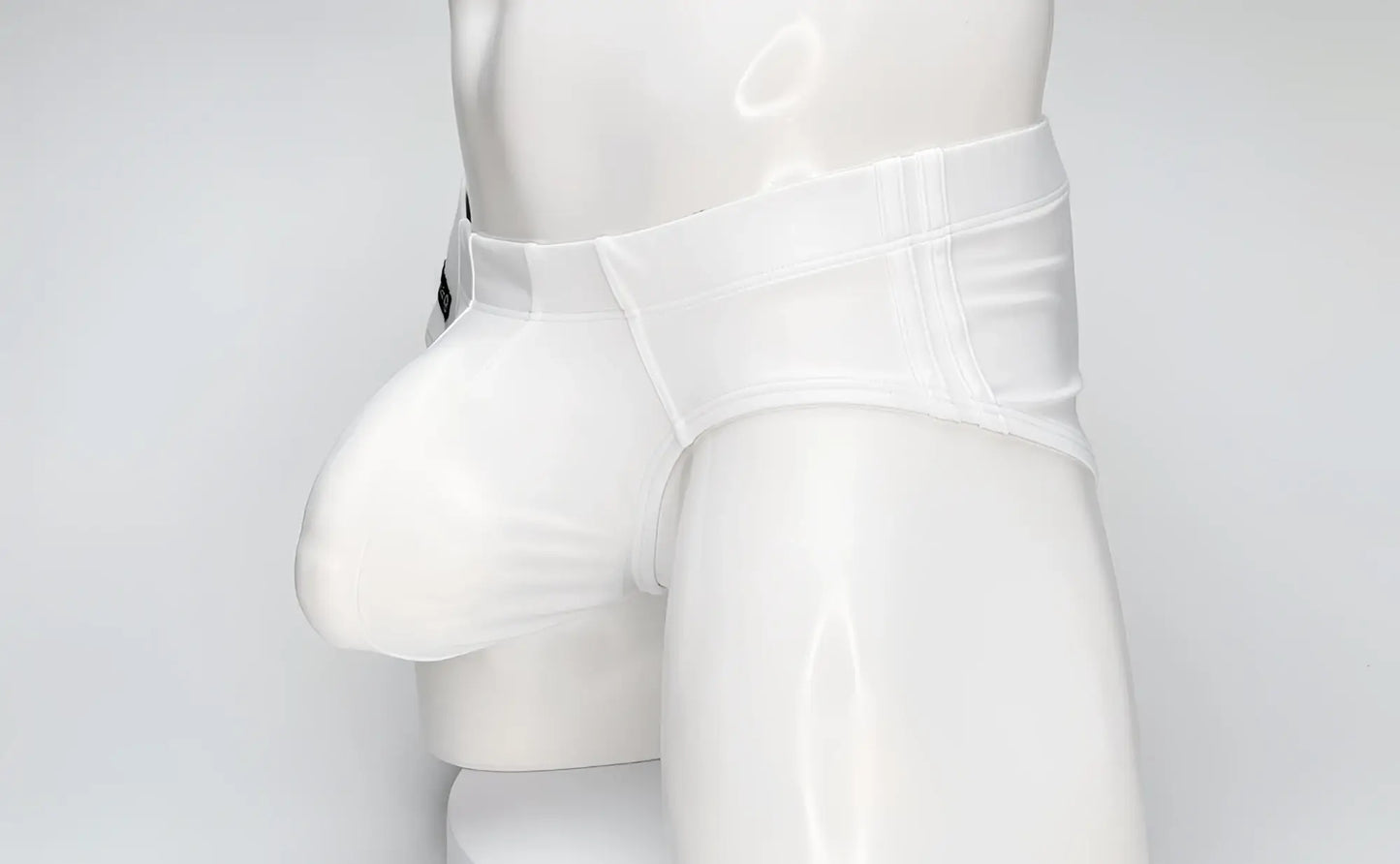 WildmanT white swim brief on a mannequin, featuring a large contoured front pouch and structured waistband.