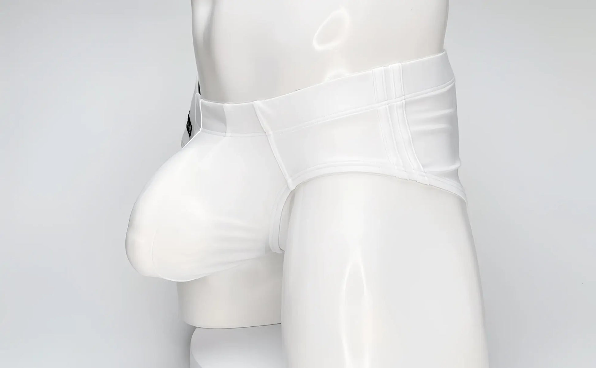 WildmanT white swim brief on a mannequin, featuring a large contoured front pouch and structured waistband.