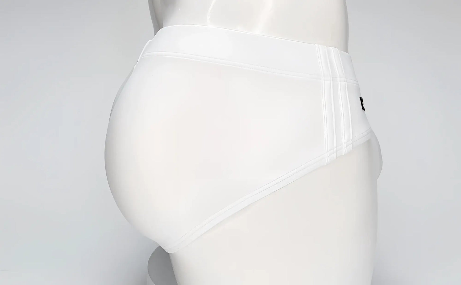 White WildmanT swim brief on a mannequin, featuring a contoured pouch design and side-stitched detailing.