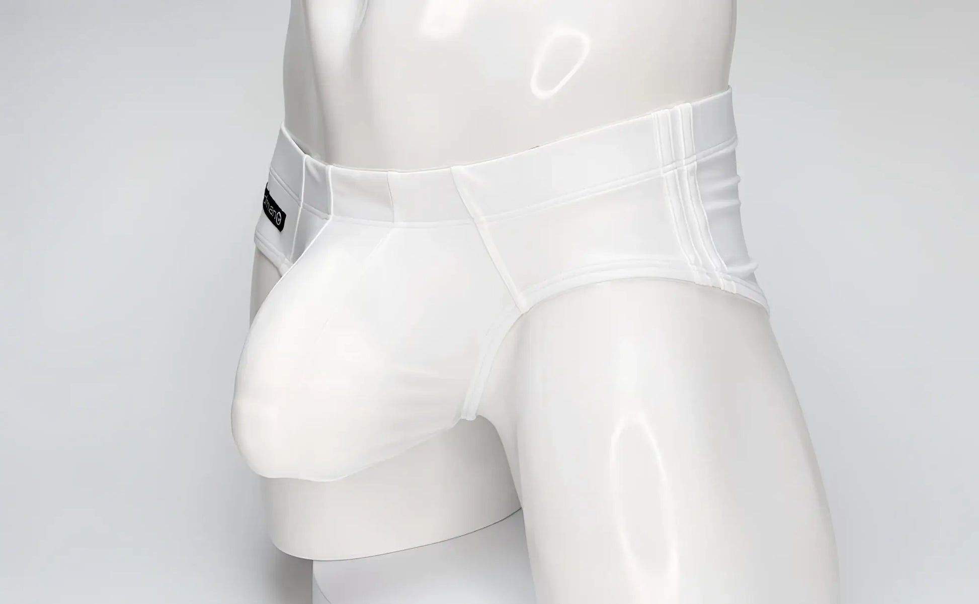 White WildmanT swim brief on a mannequin, featuring a contoured, prominent front pouch and side branding tag.