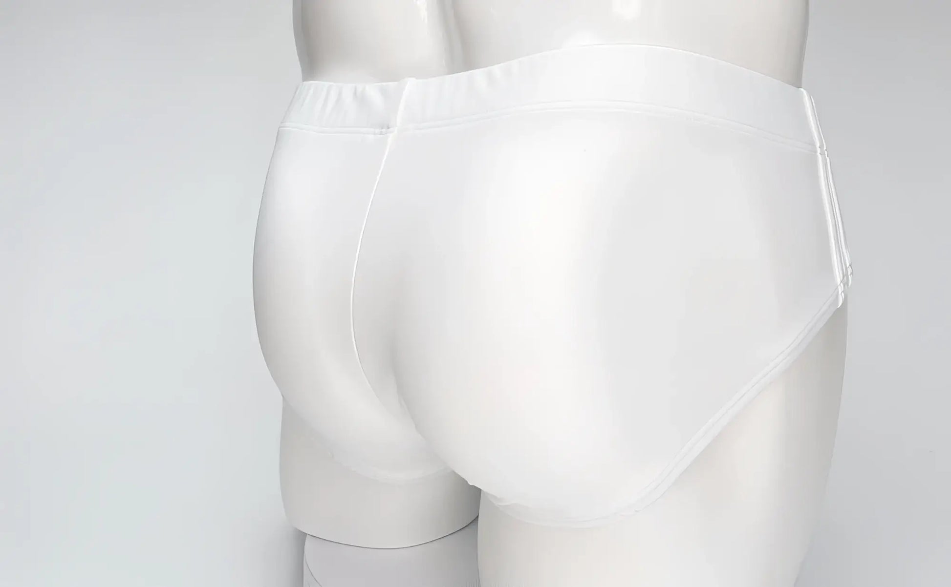 Back view of plain white WildmanT Big Boy swim brief on a mannequin, featuring a smooth, form-fitting design.