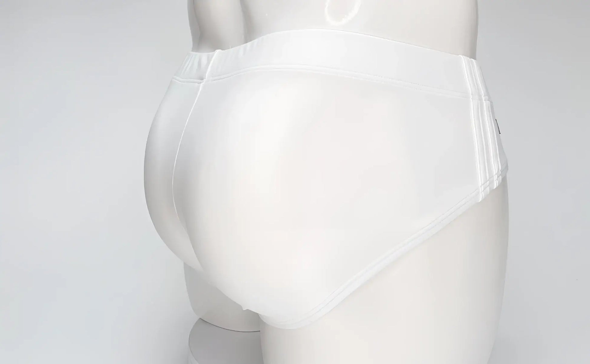 Back view of WildmanT white swim brief on a mannequin, featuring full coverage and elastic waistband.