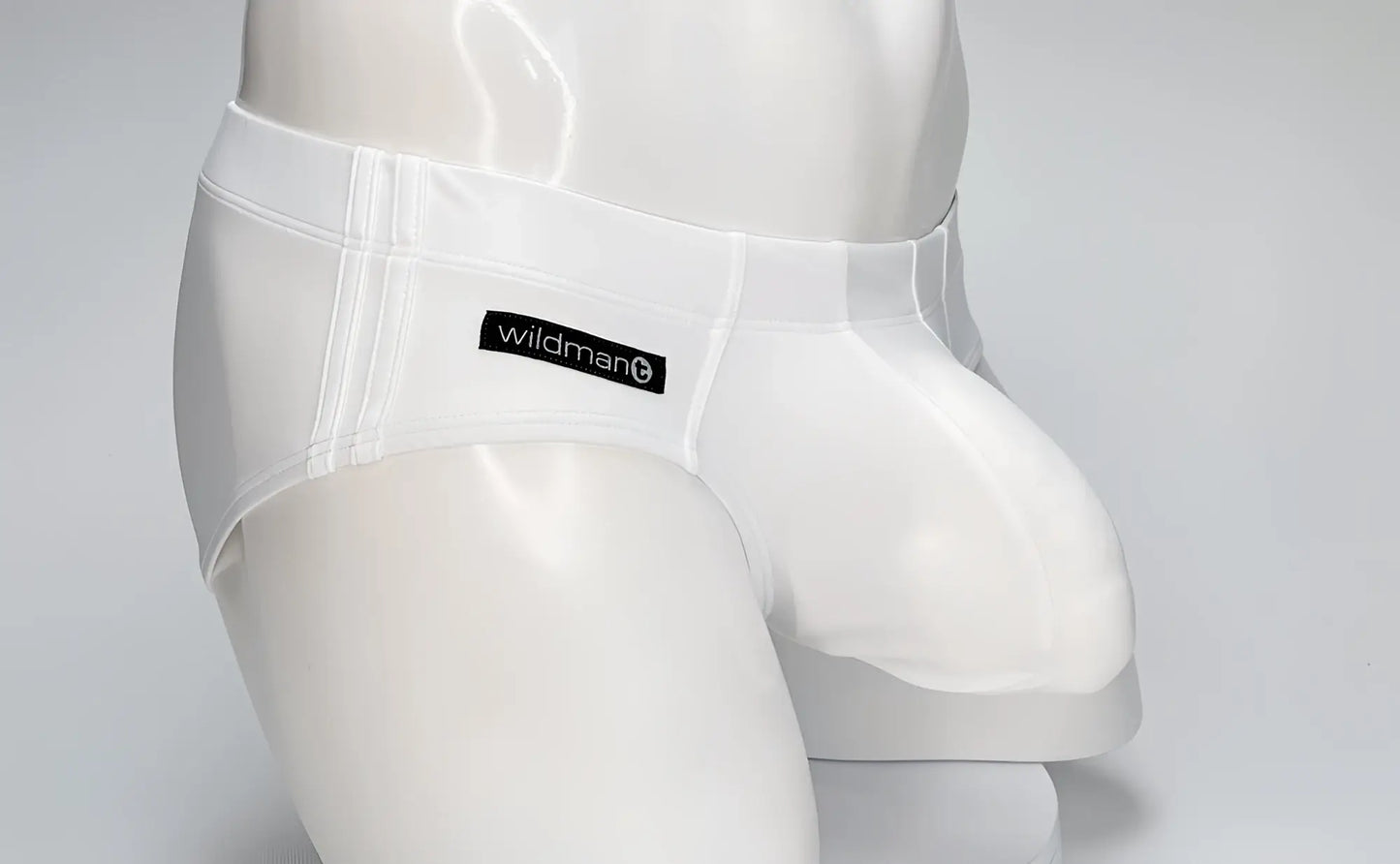 White WildmanT swim brief on a mannequin, featuring a contoured, prominent pouch and a black logo tab on the hip.