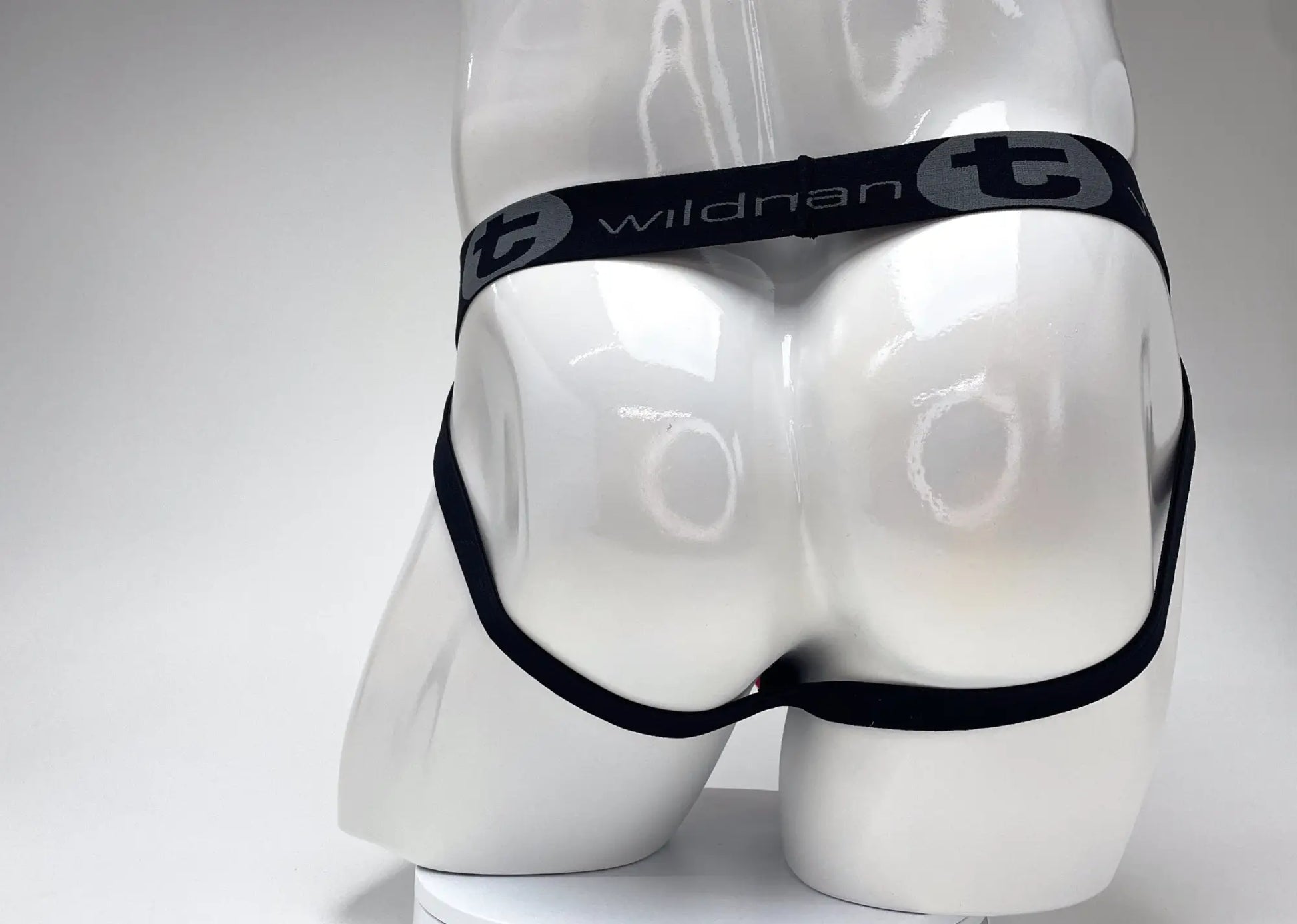 Black elastic waistband with wildman t branding in white on a red and black cotton big boy pouch stripe jockstrap
