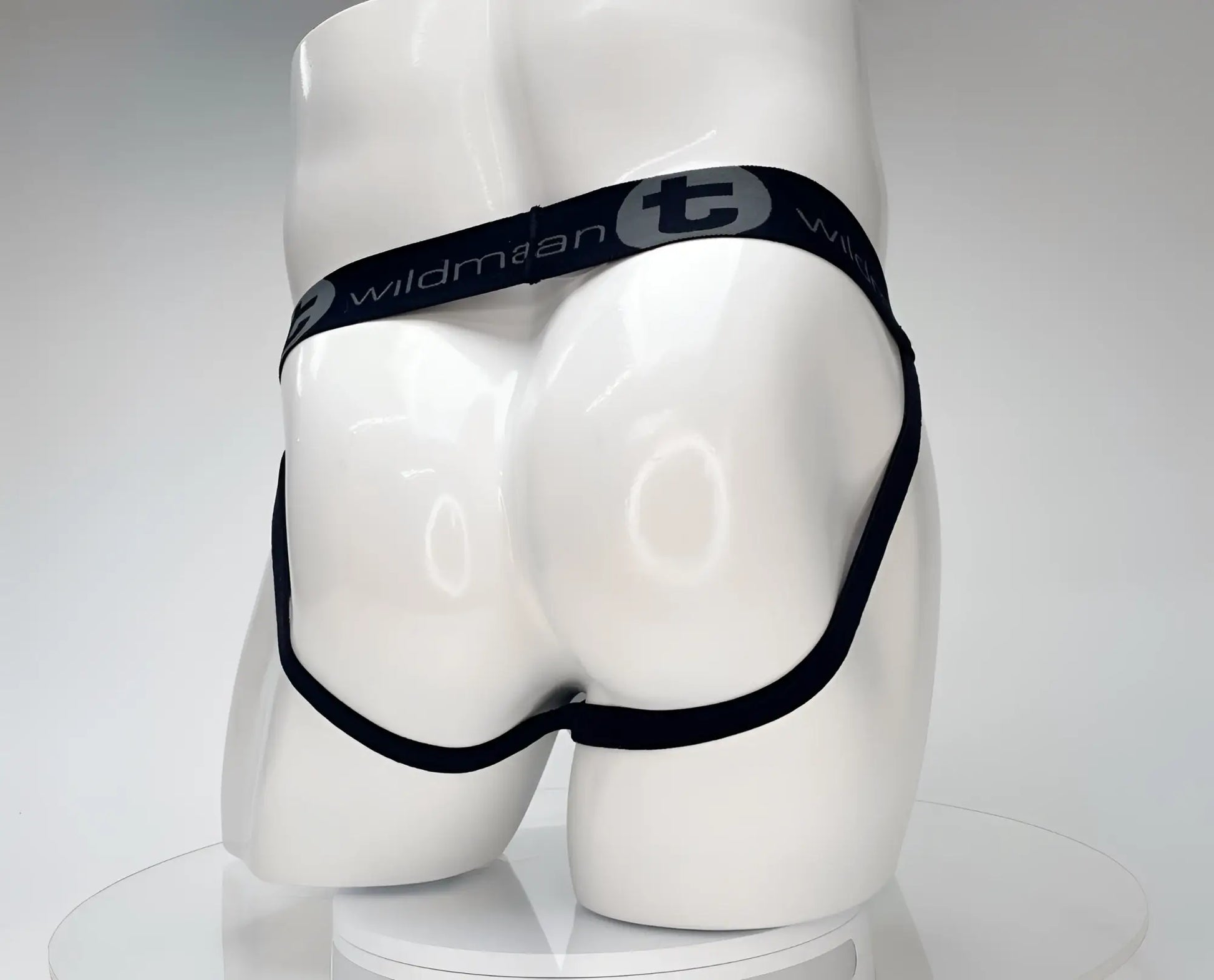 White jockstrap on a mannequin, featuring a black waistband with WildmanT logo and thin black leg straps.