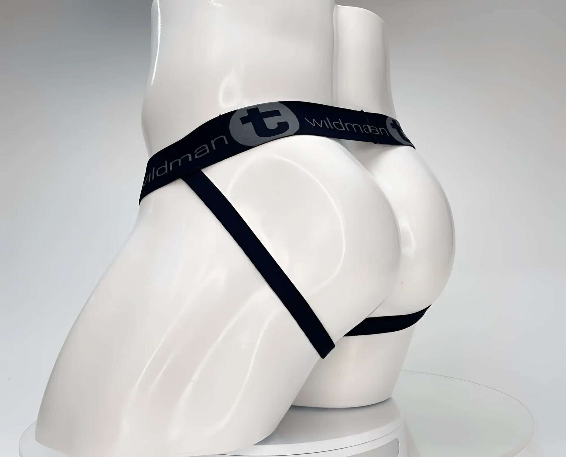 Black elastic waistband with wildman branding on white mannequin of wildmant cotton monster cock jockstrap white