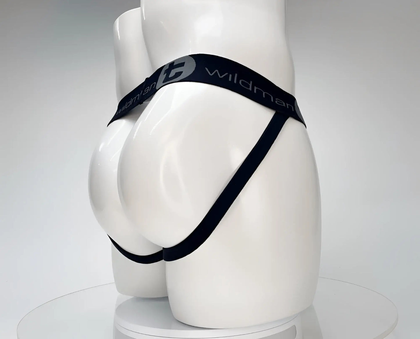 White WildmanT jockstrap on a mannequin, featuring a black branded elastic waistband and side straps.