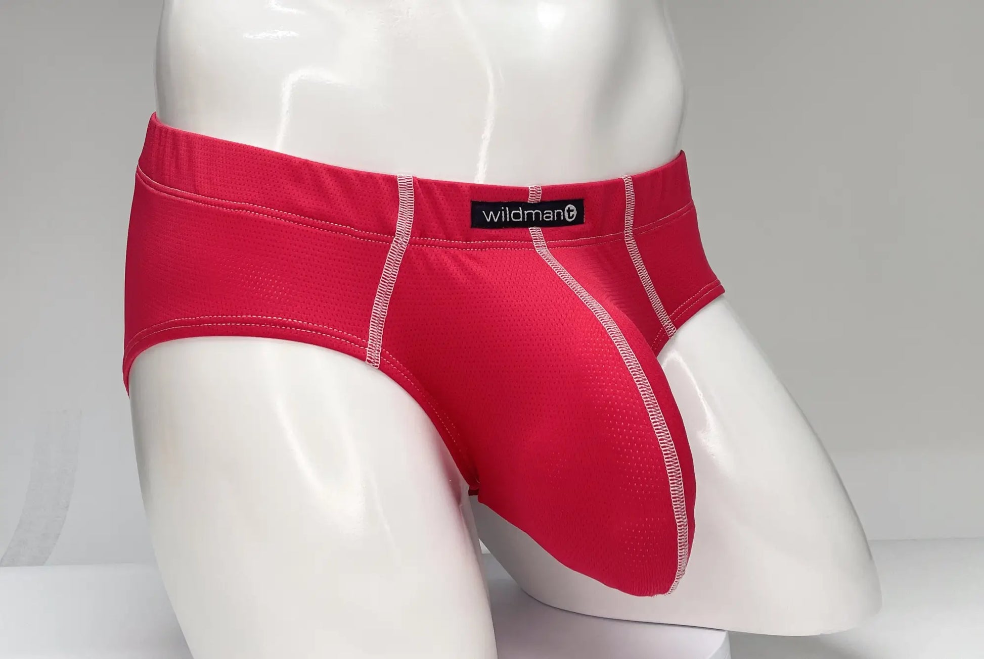 Red wildman brand mesh briefs with white stitching featuring a breathable mesh-like texture in wildmant mesh brief red
