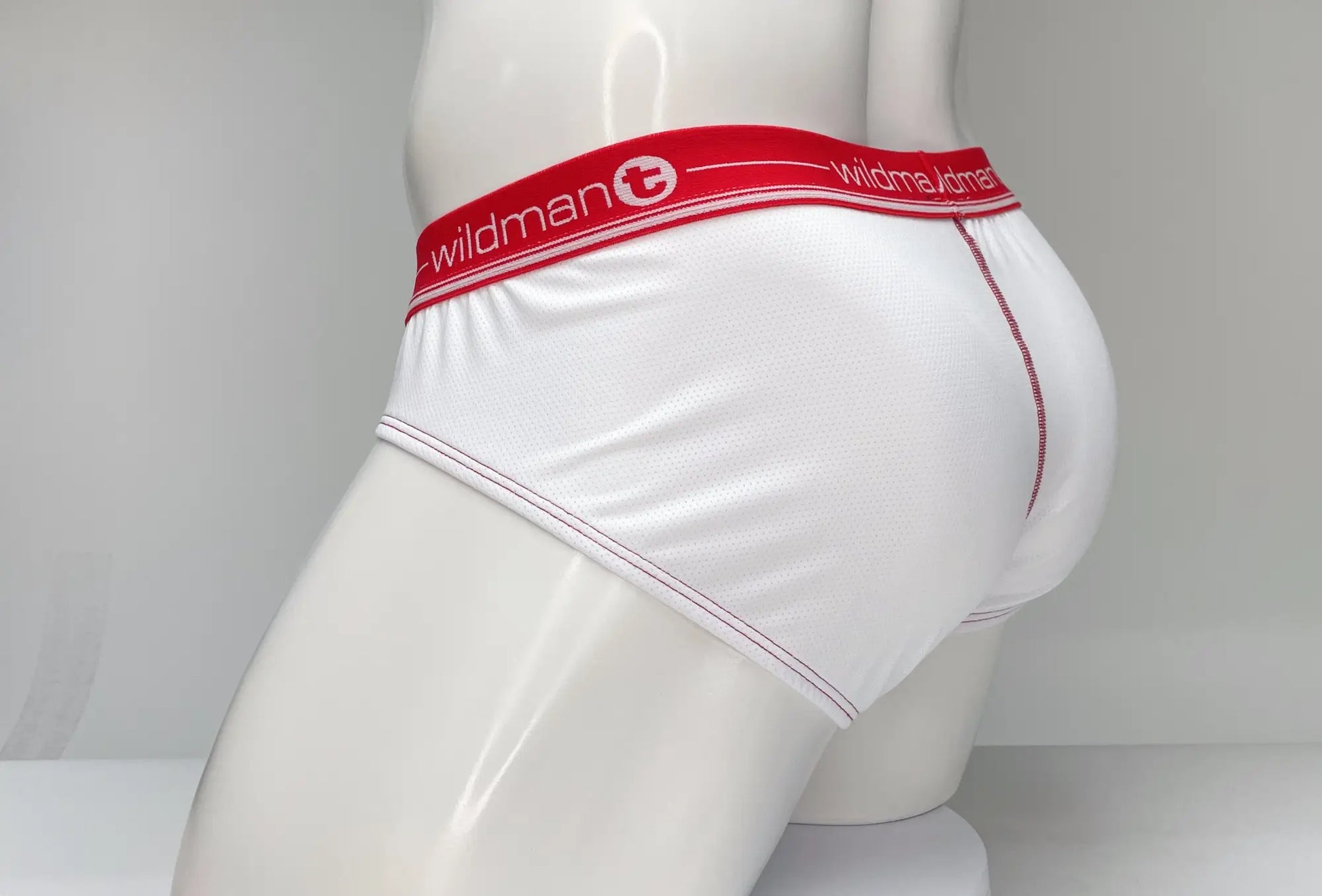 White men’s mesh briefs with red elastic waistband featuring wildman brand logo and text wildmant mesh brief white and red