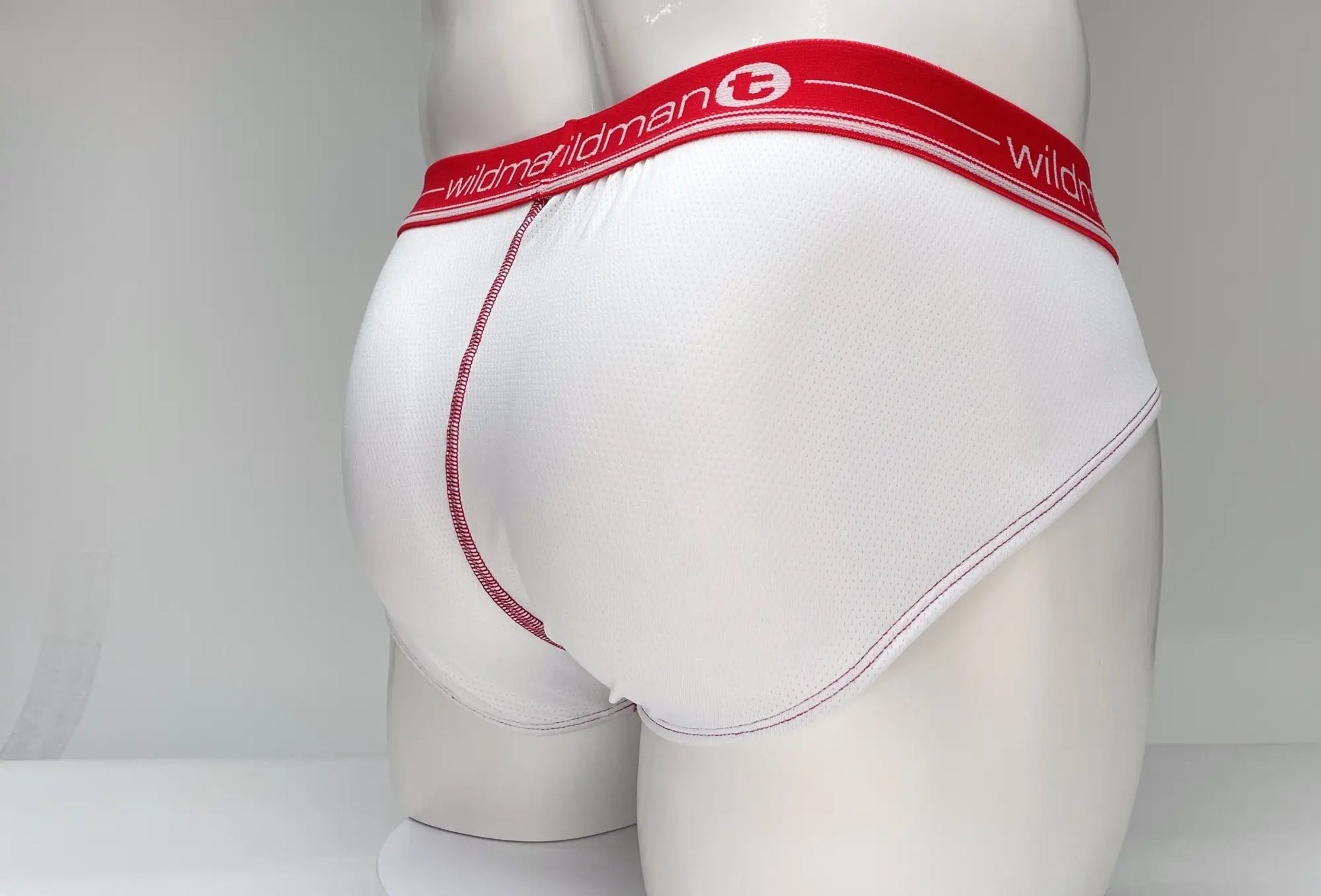 White briefs with red waistband featuring wildman brand name and logo mesh material for breathability