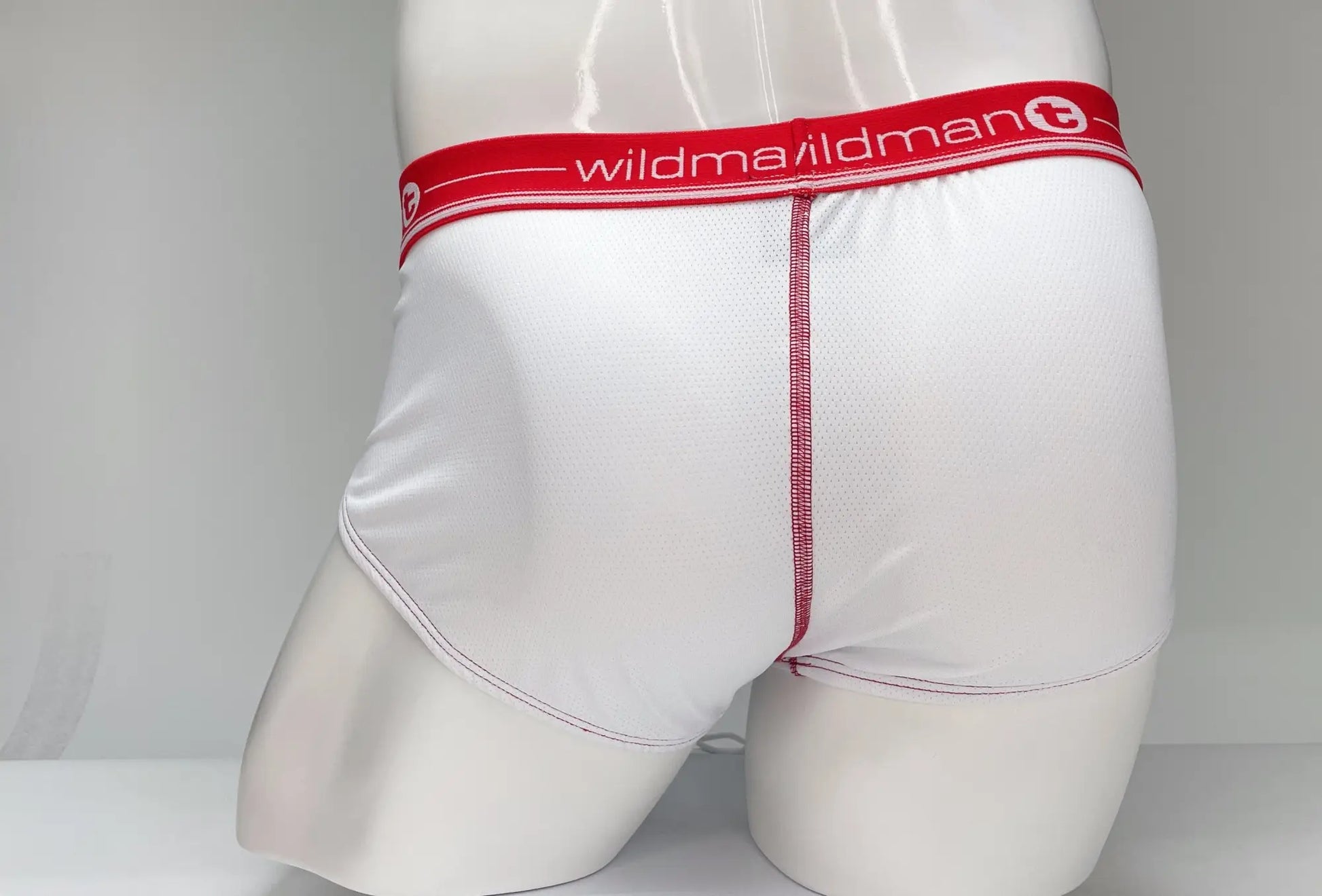 White briefs with a red waistband featuring the wildman mesh logo made of smooth fabric