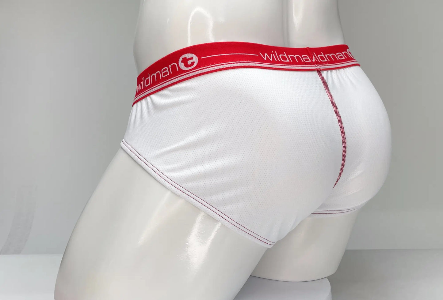 White wildman mesh briefs with a red waistband featuring wildman logo and pink stitching detail along the side seam