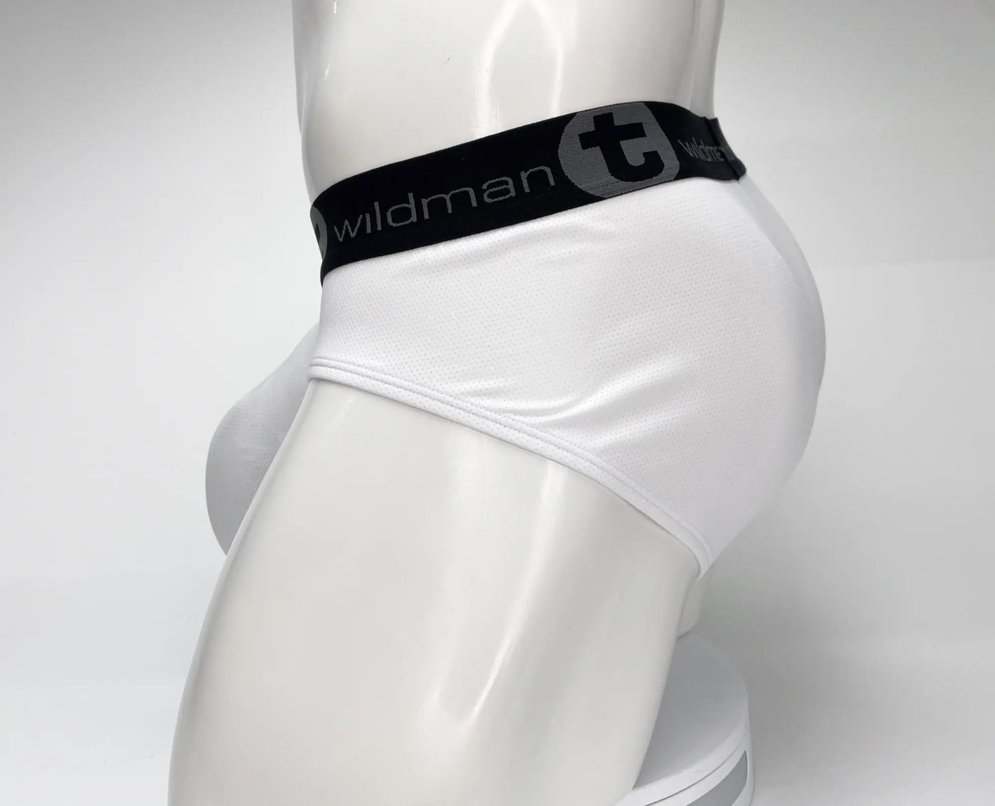 White mens mesh briefs with black waistband featuring wildman logo and stylized t emblem in wildmant mesh monster cock brief white