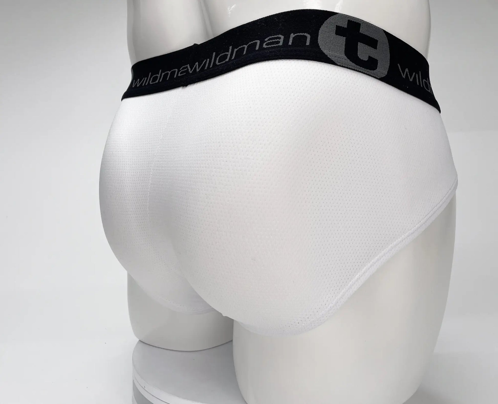 White men’s mesh briefs with black elastic waistband featuring wildman brand name and logo wildmant mesh monster cock brief white