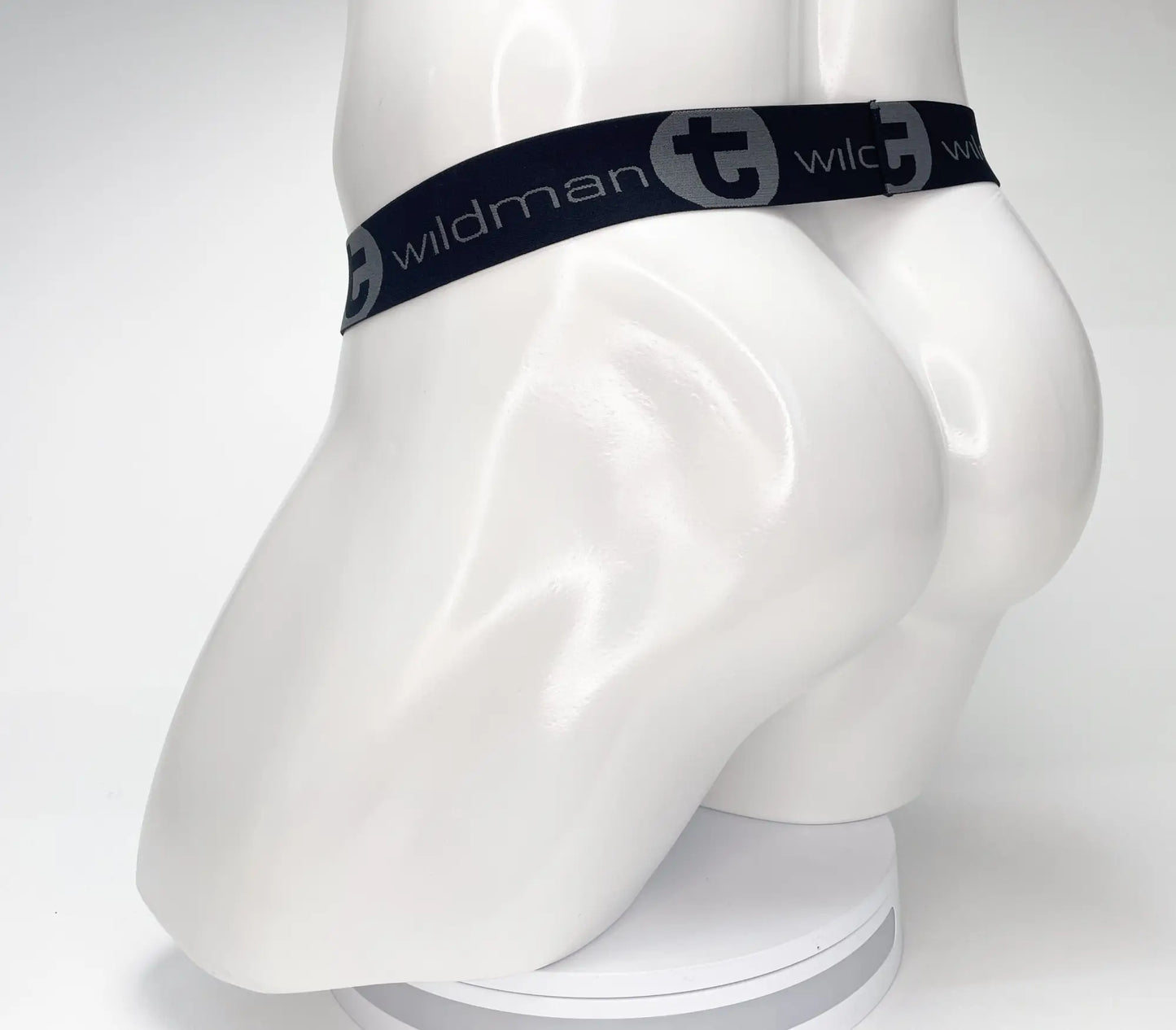 Black elastic waistband with wildman branding and stylized t logo on white mannequin of wildmant mesh monster cock strapless pouch black