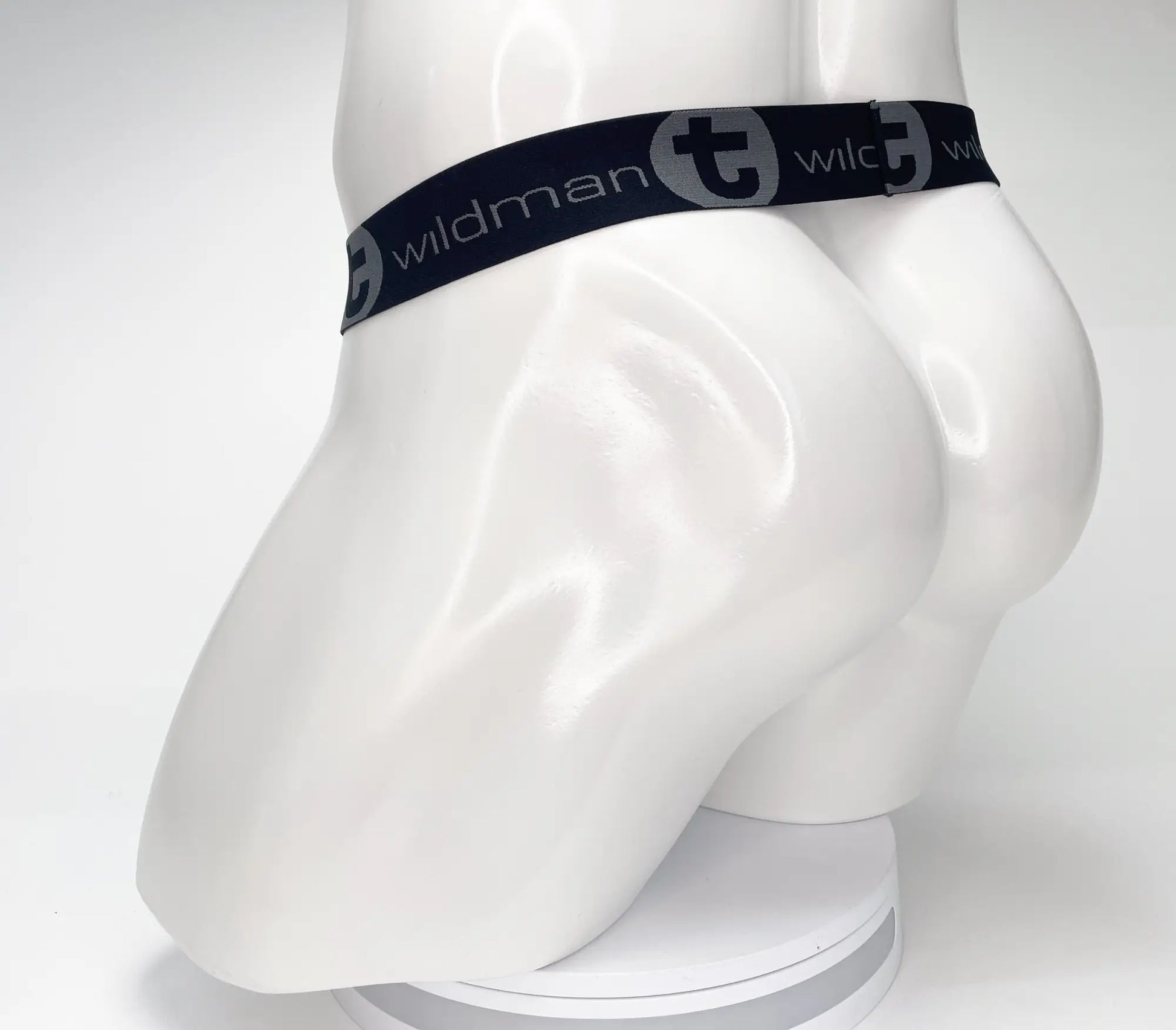 Black elastic waistband with wildman branding and stylized t logo on white mannequin of wildmant mesh monster cock strapless pouch black