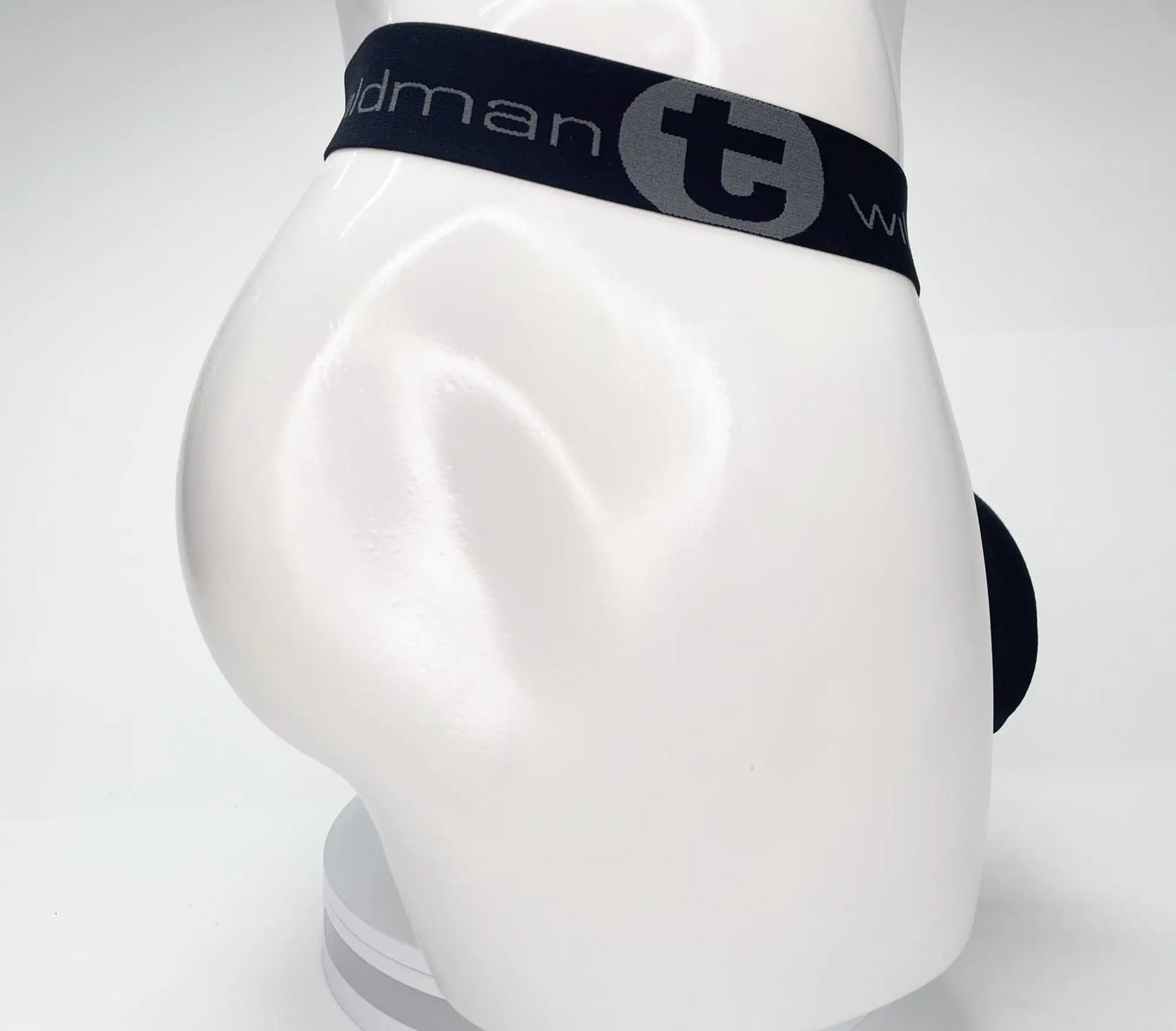 Black men’s briefs with a navy blue waistband featuring the t logo from wildmant mesh monster cock strapless pouch black
