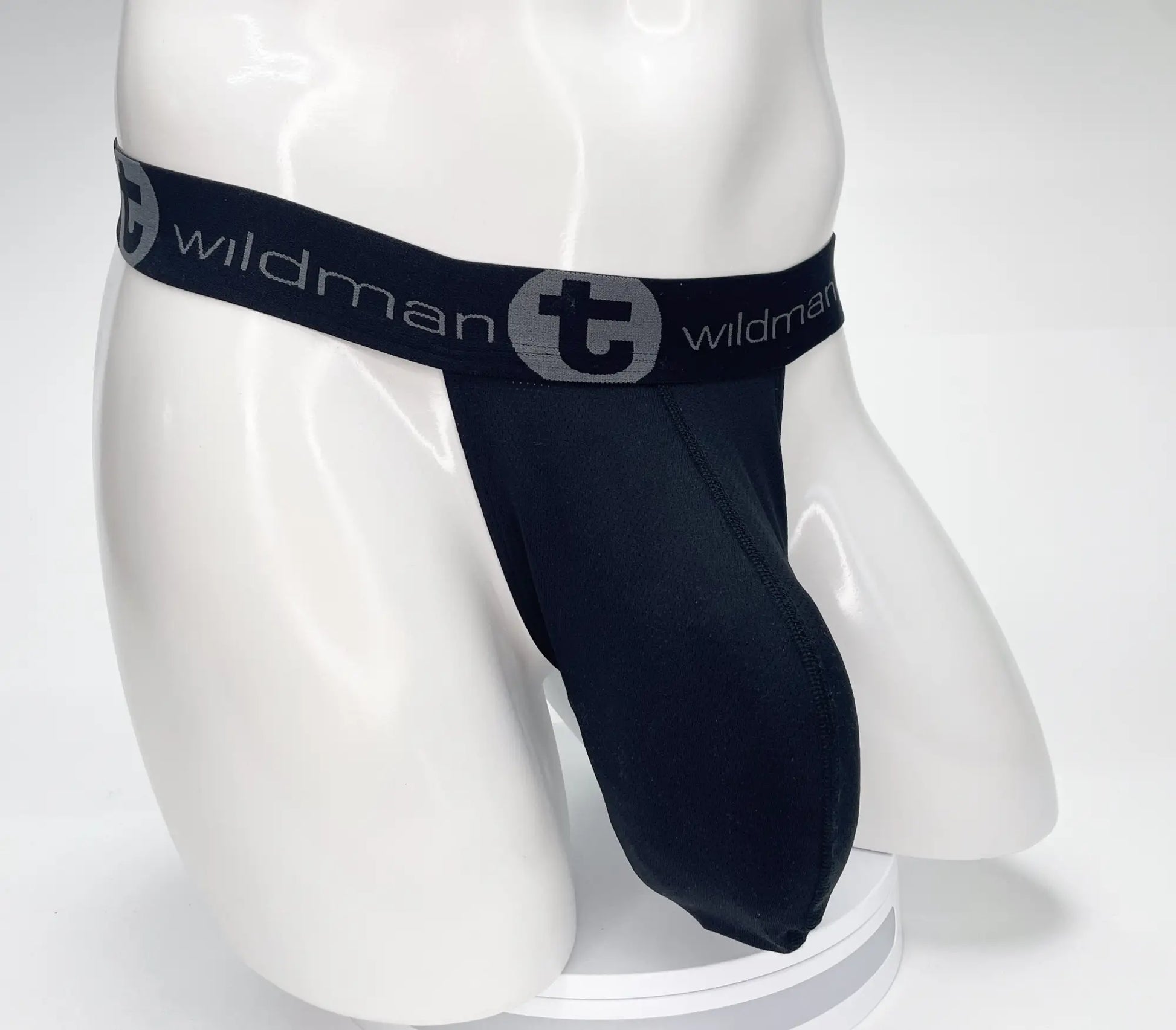 Black wildman brand thong with stretchy elastic waistband featuring gray logo and name in wildmant mesh monster cock strapless pouch black