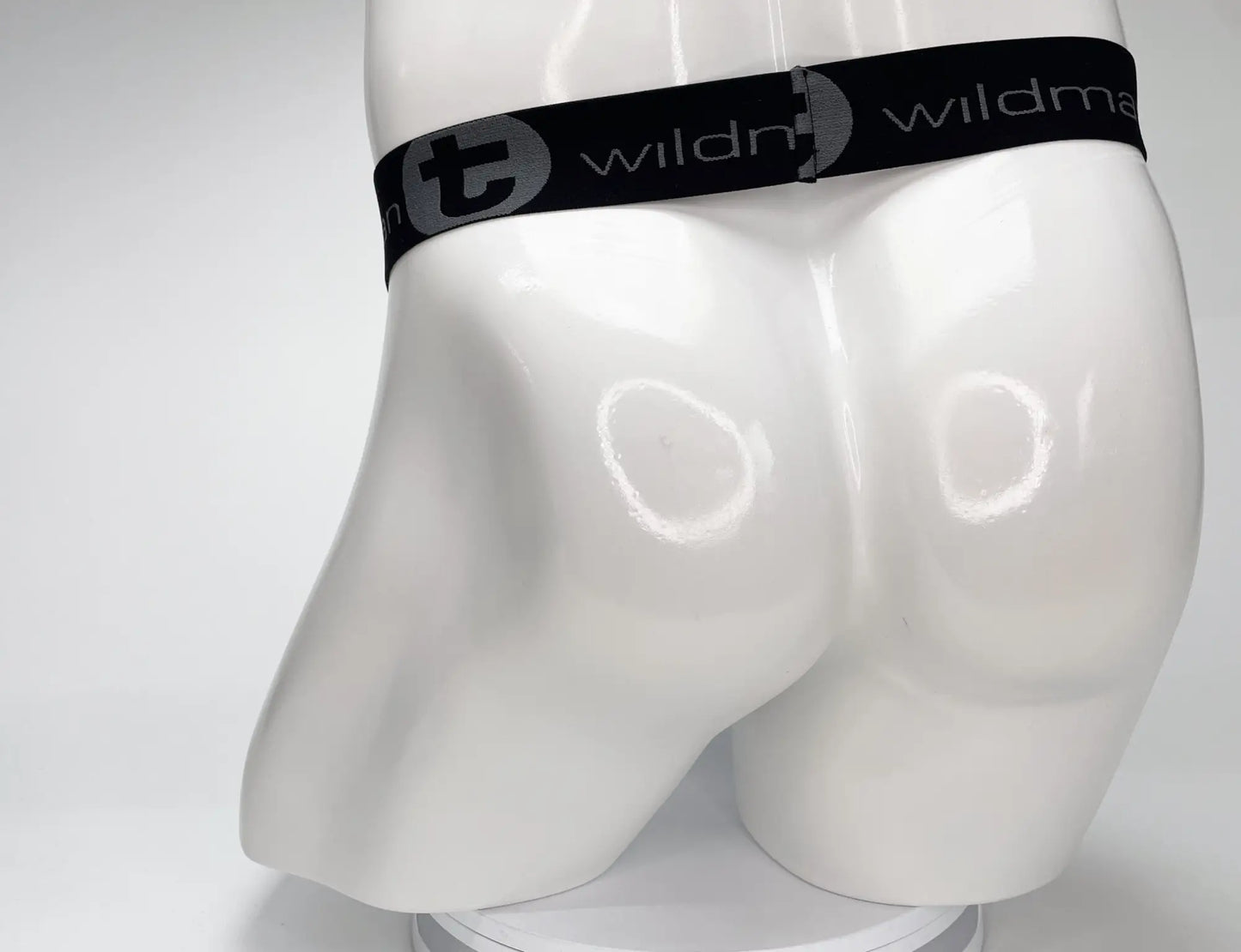 Black elastic waistband with wildman branding and circular logo on white mannequin wearing wildmant mesh monster cock strapless pouch white
